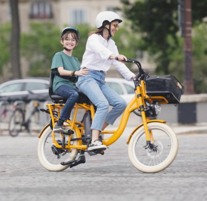Un vélo électrique jaune avec deux femmes dessus